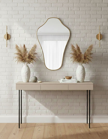 Sculpted crest brass mirror displayed above console table with neutral decor