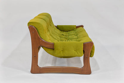 Green cushioned chair with wooden frame on a white background