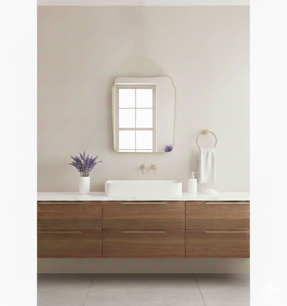 Rounded crest rectangle brass mirror styled above a floating wooden bathroom vanity
