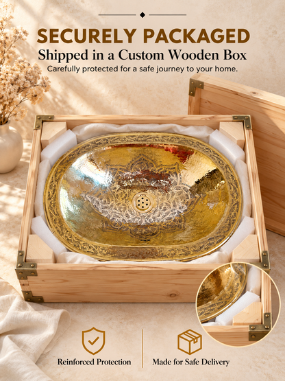 Oval engraved brass sink cushioned with fabric and foam inside an open wooden box, with text highlighting secure packaging and safe delivery.