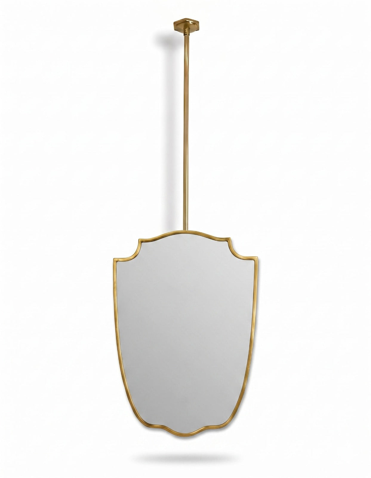 Gold framed shield mirror suspended from ceiling rod on white background