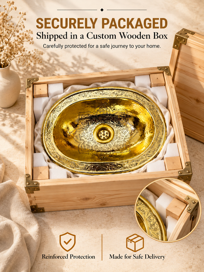 Engraved oval brass sink cushioned with fabric and foam inside an open wooden shipping box, with text highlighting secure packaging and reinforced protection.