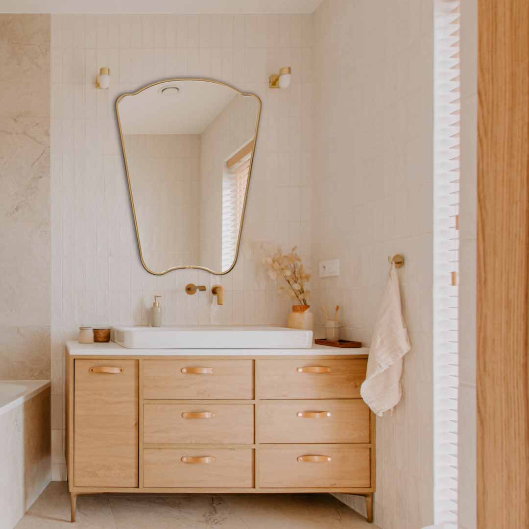 Irregular Mirror hanging on bathroom  , brass faucet and sink 