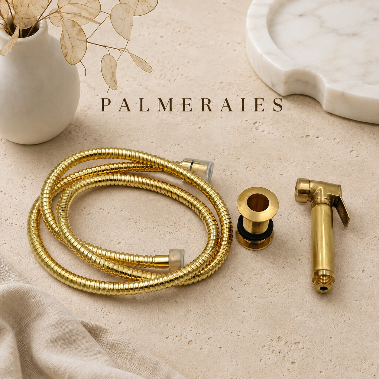 Solid brass kitchen side sprayer with matching brass hose and mounting sleeve displayed on a neutral stone surface with luxury styling accessories.