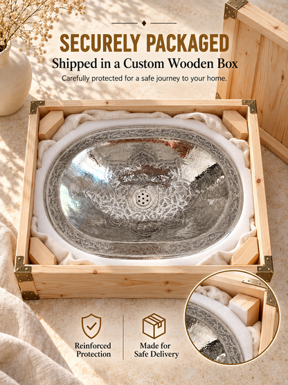 Engraved oval silver sink cushioned with foam and fabric in a wooden shipping box, with text highlighting secure packaging and safe delivery.