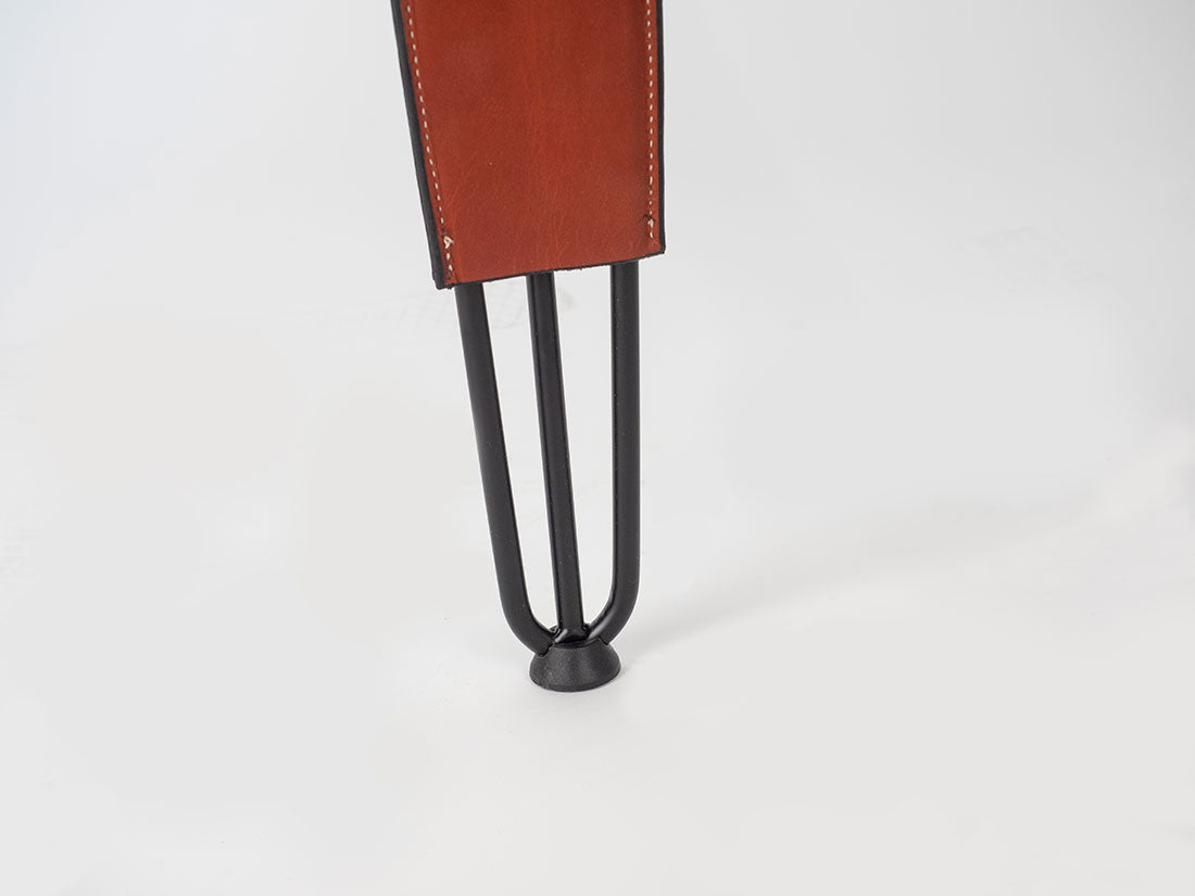Brown leather-bound book with a black metal stand on a white background