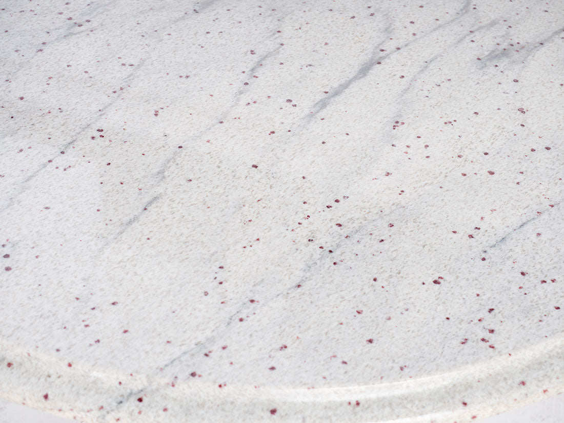 Close-up of a textured white surface with subtle red specks