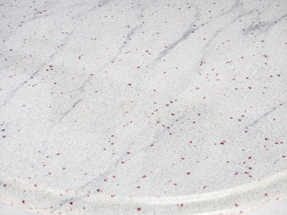Close-up of a textured white surface with subtle red specks