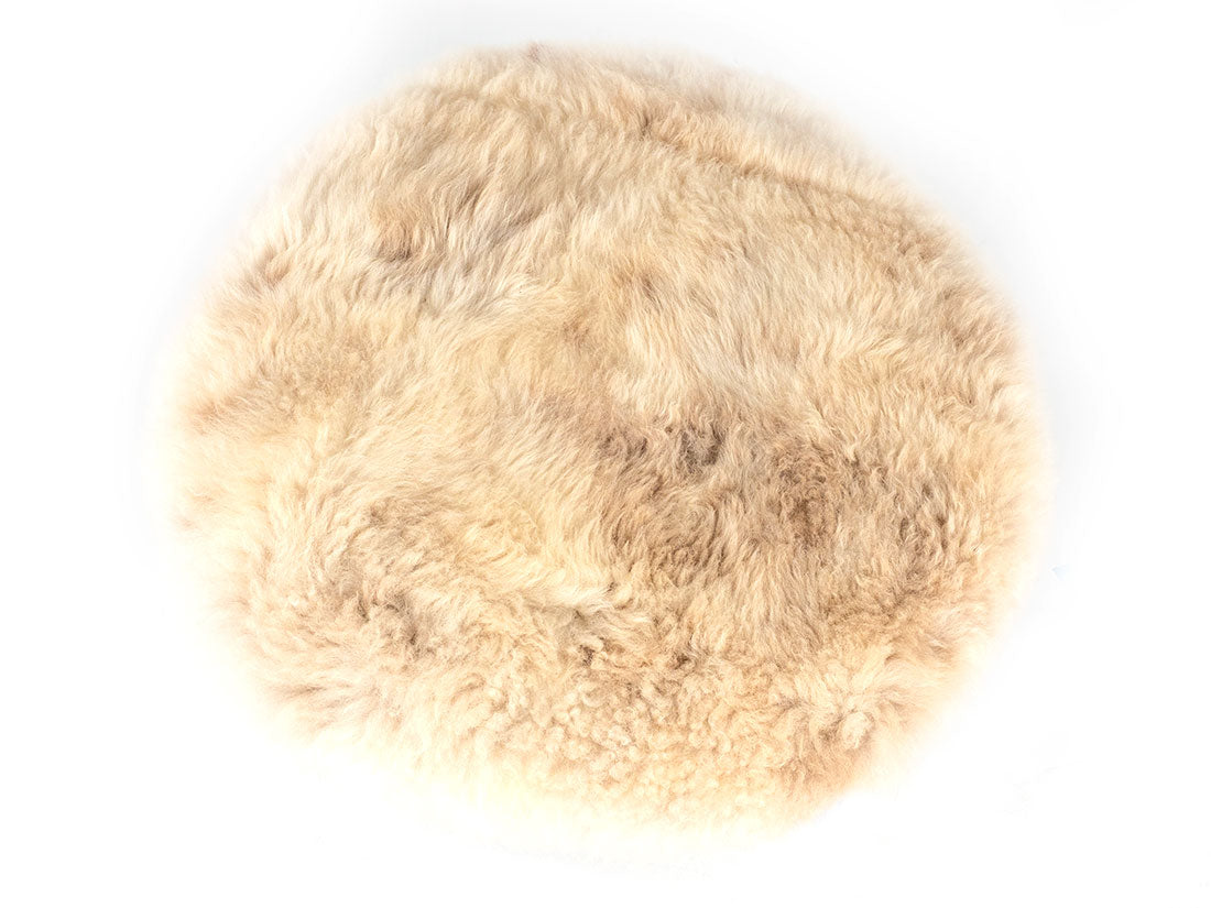 Round beige fur rug on a white background
