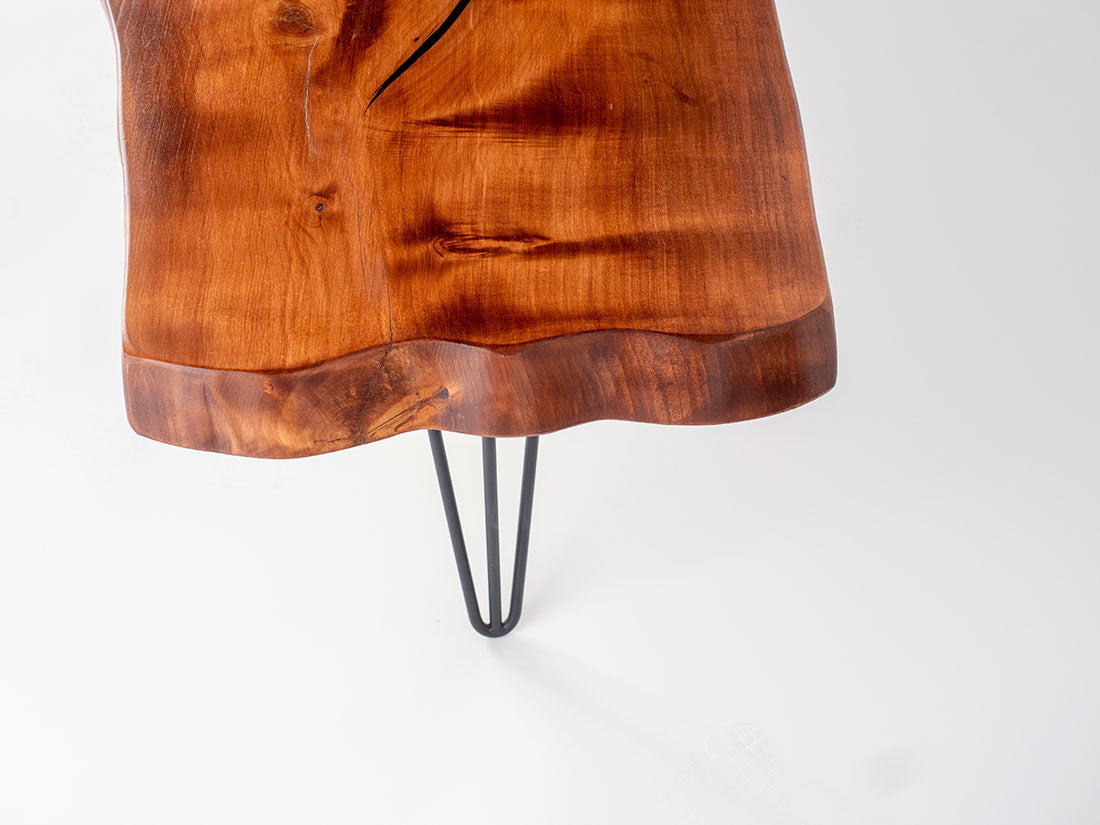 Wooden table with a natural edge and metal hairpin legs on a white background