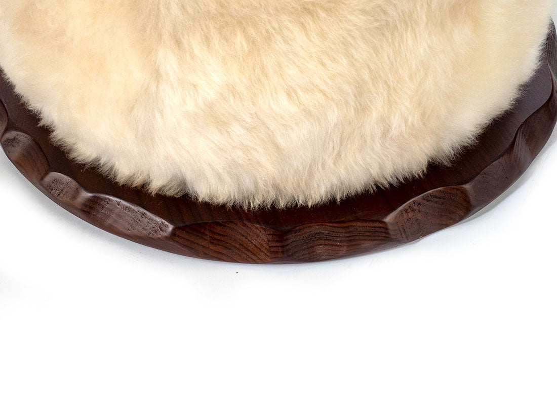 Round wooden coaster with a fur-like top on a white background