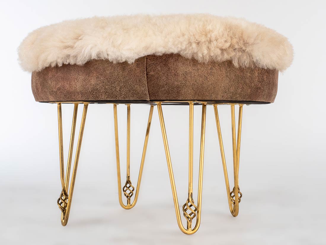 Stool with brown cushioned top and gold hairpin legs on a white background