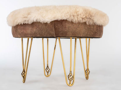 Stool with brown cushioned top and gold hairpin legs on a white background