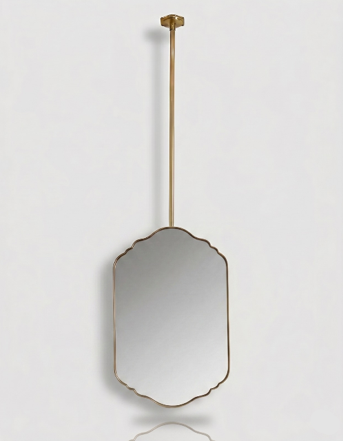 Suspended scalloped brass vanity mirror with a slim gold frame and ceiling-mounted brass rod on a white background.