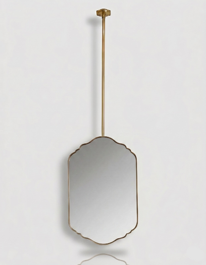 Suspended scalloped brass vanity mirror with a slim gold frame and ceiling-mounted brass rod on a white background.