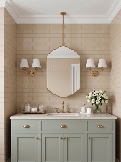 Decorative hanging brass mirror with scalloped edges above a sage green vanity in a classic bathroom.