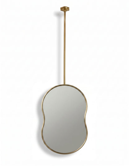 Handmade organic oval brass mirror with slim brass frame and ceiling-mounted suspension rod.