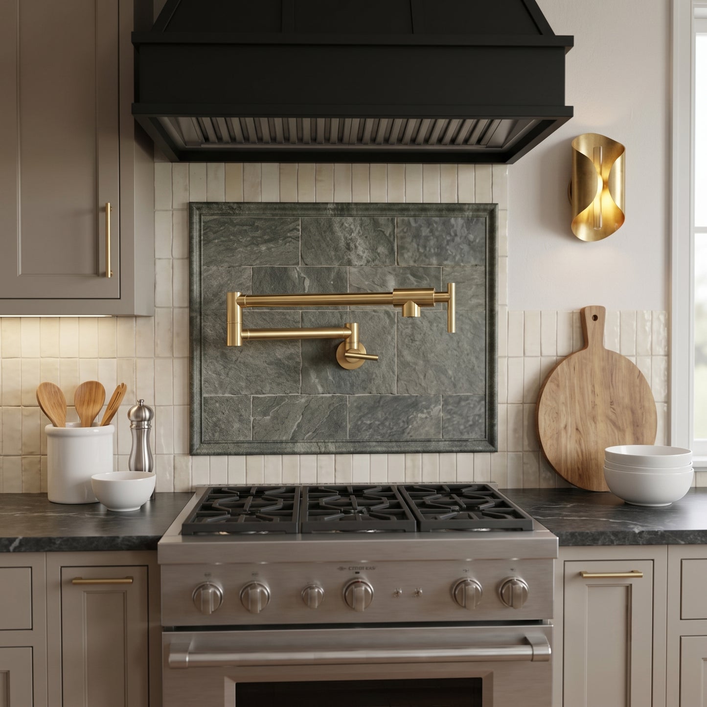 Wall-mounted unlacquered brass pot filler faucet installed above a professional gas range in a luxury kitchen with white tile backsplash, black range hood, and warm brass accents.