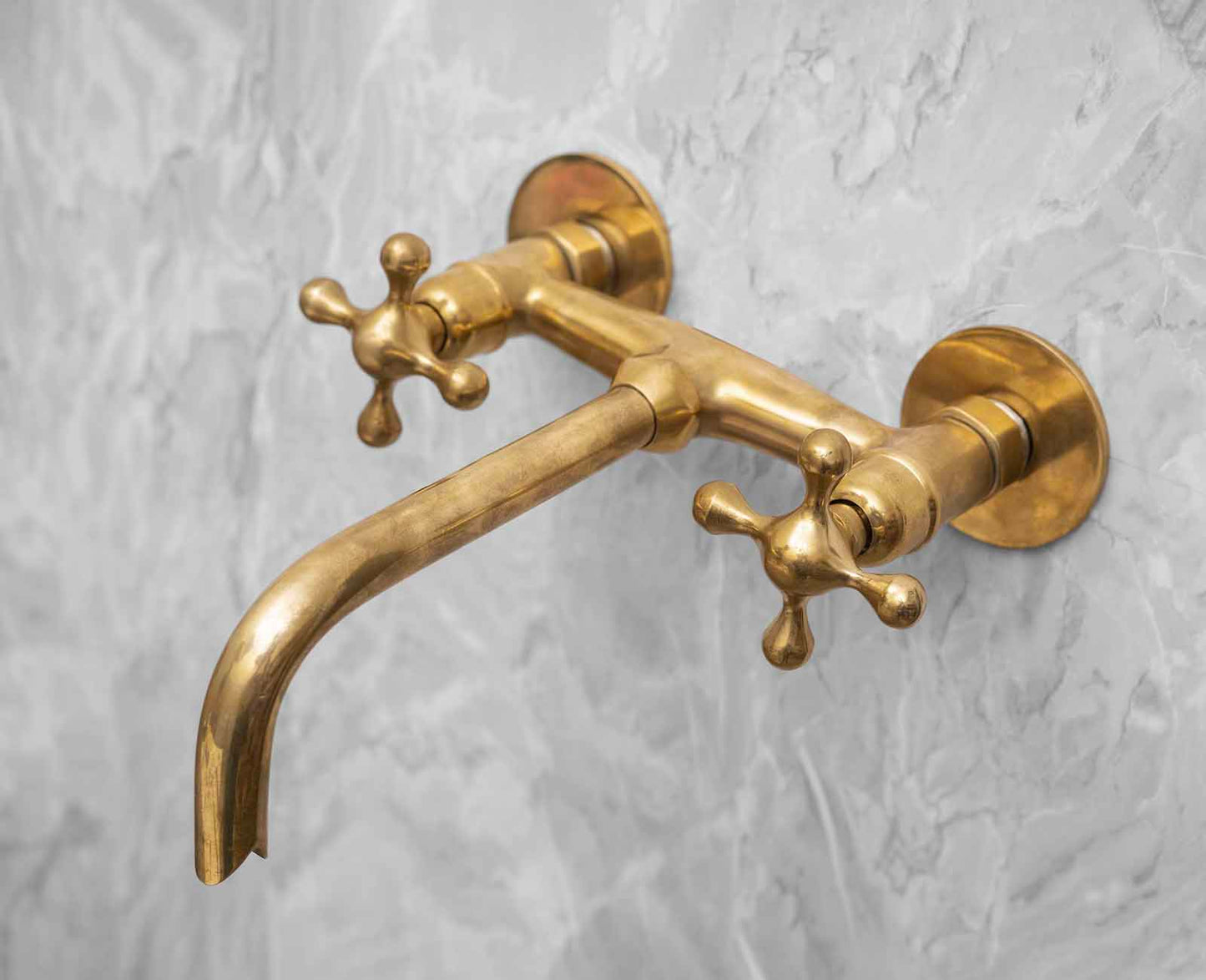 a gold faucet on a white marble wall