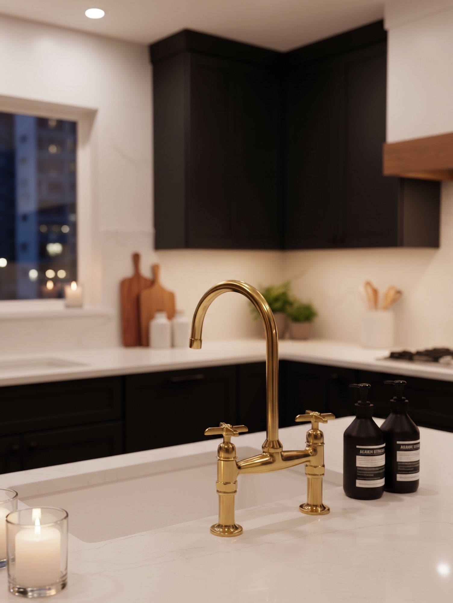 Polished unlacquered brass bridge kitchen faucet installed on a white quartz island in a modern black kitchen with warm ambient lighting.