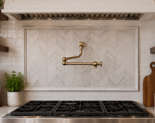 Solid brass folding pot filler installed above a luxury stove range with white herringbone marble backsplash.