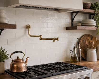 Solid brass wall mounted pot filler faucet installed above a professional gas range with white subway tile backsplash.