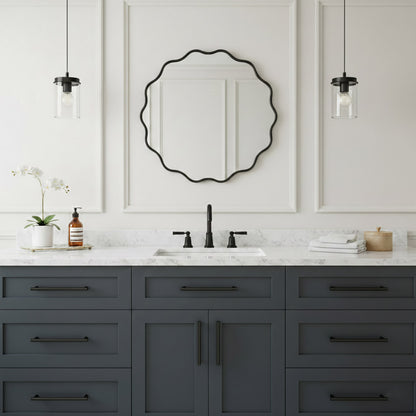 Round wavy black wall mirror over gray vanity in modern white bathroom.