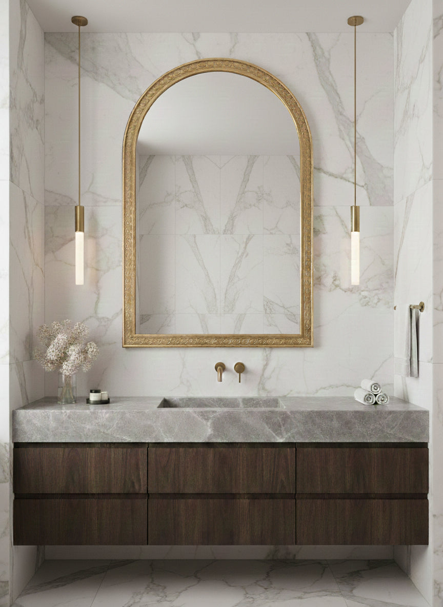 Large brass arch mirror above marble vanity