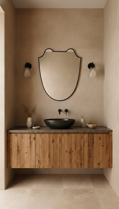 Black brass Italian shield mirror above a wooden bathroom vanity