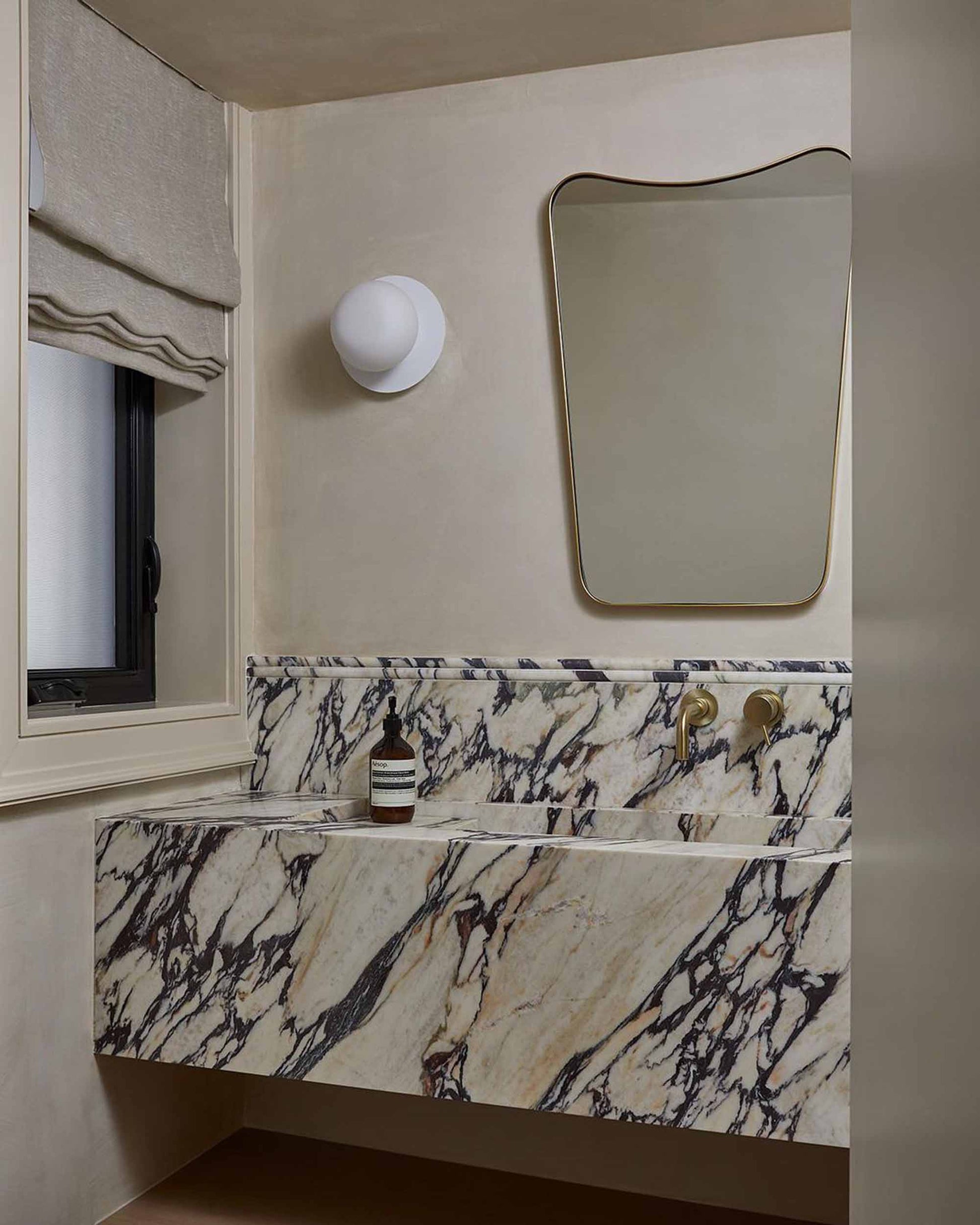 curved brass mirror in powder room