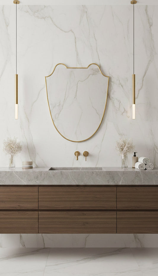 Curved brass mirror above walnut vanity in marble bathroom
