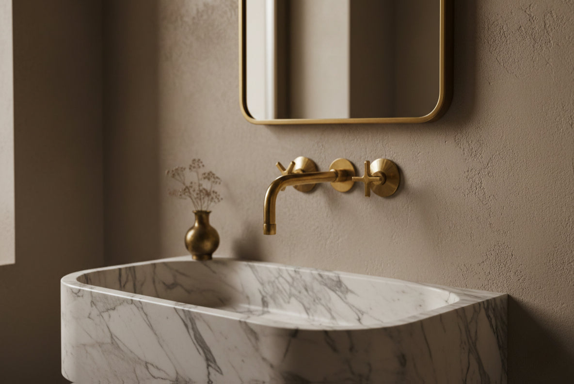 Marble trough sink with minimalist brass wall-mounted faucet and soft neutral wall.