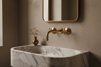 Marble trough sink with minimalist brass wall-mounted faucet and soft neutral wall.
