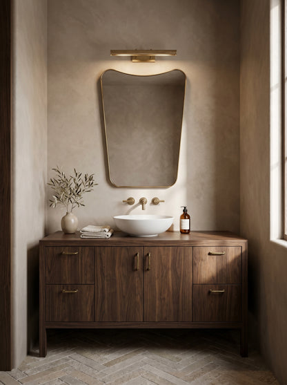 Modern brass wall mirror above walnut bathroom vanity