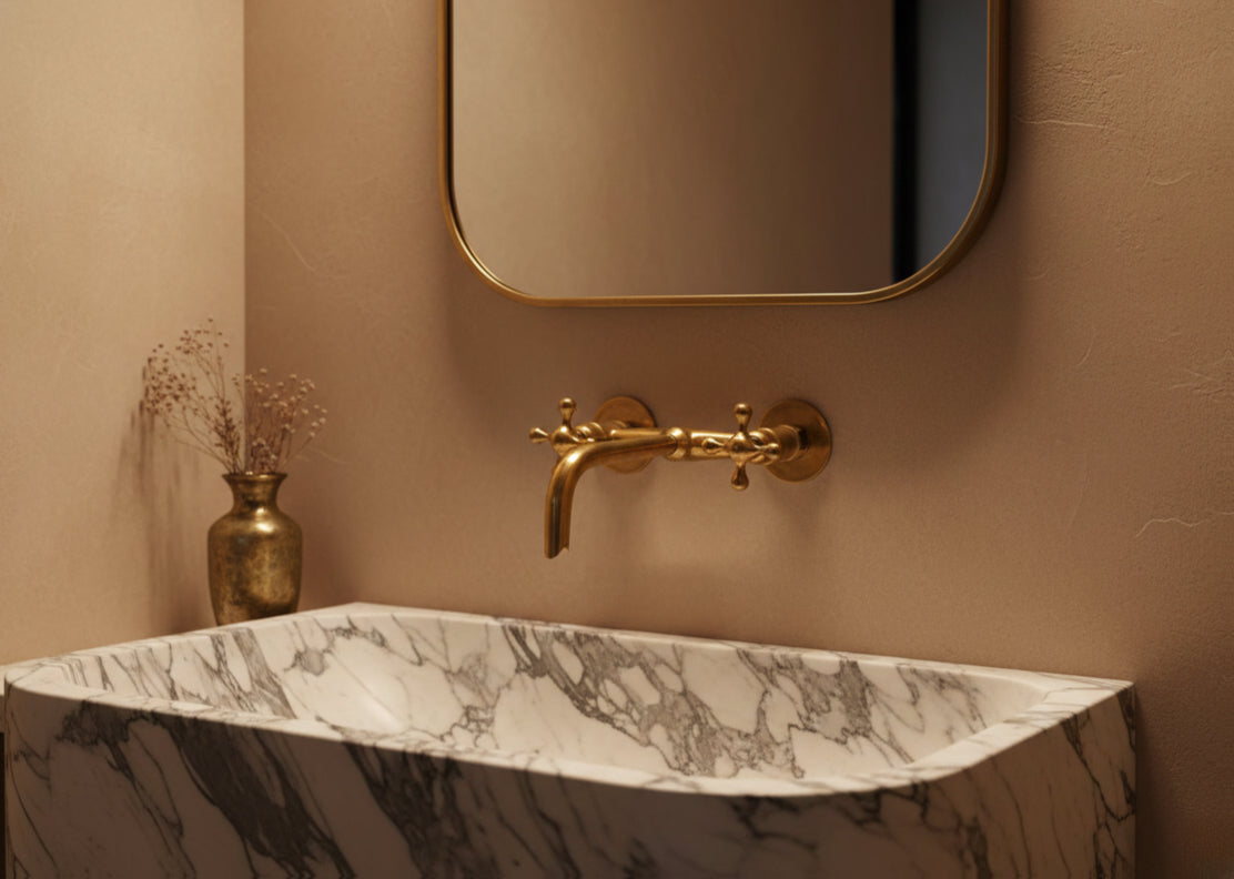 Classic brass wall faucet above marble basin with warm ambient lighting.