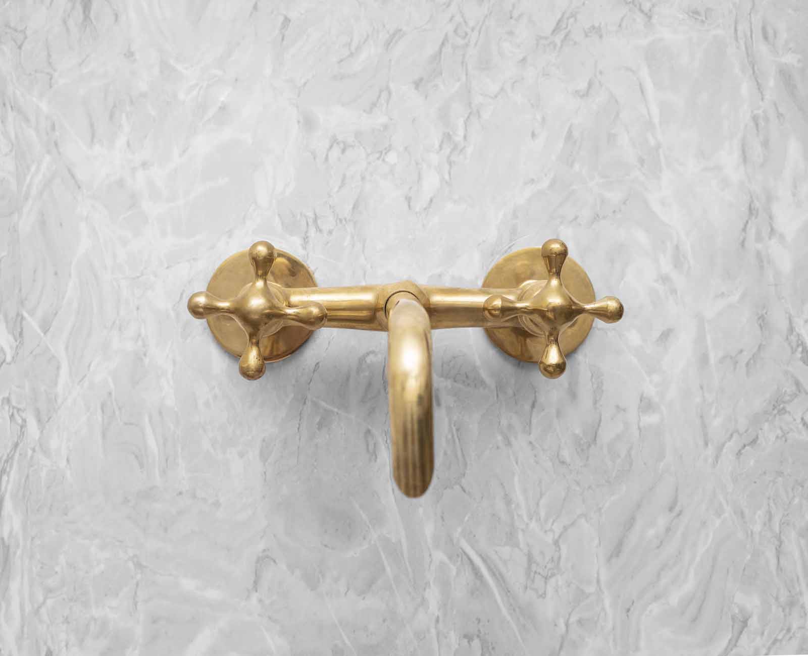 a golden metal hook on a white marble wall