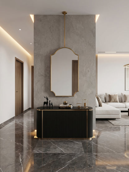 Ceiling-mounted arch brass mirror above black console table.