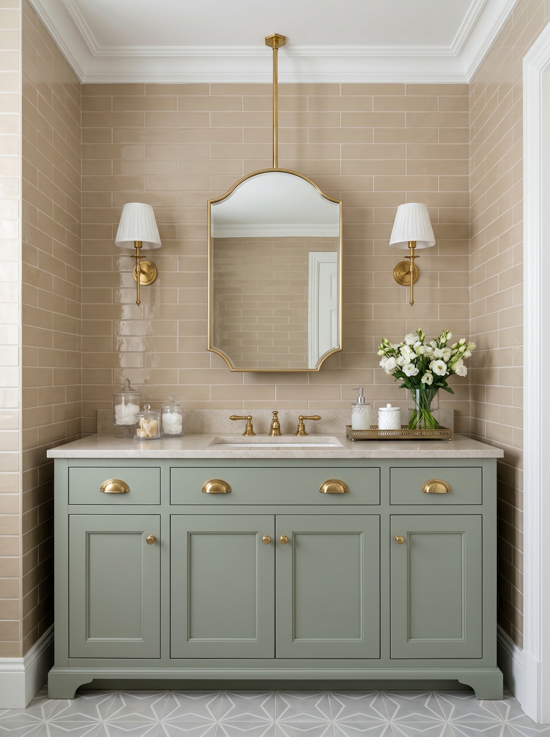 Suspended oval brass mirror above a sage green vanity with brass sconces and beige subway tile bathroom walls.