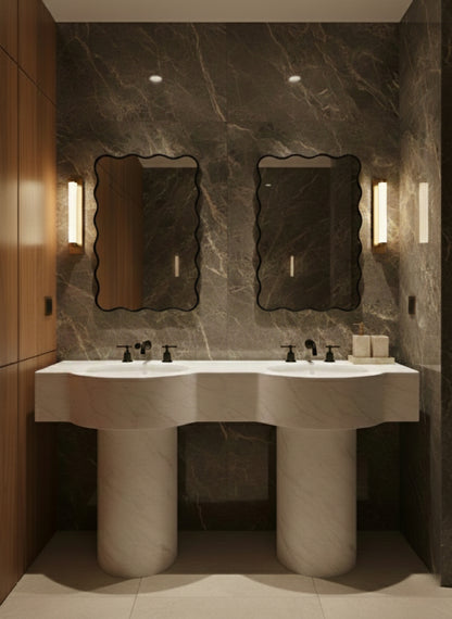 Twin black brass mirrors above double pedestal sinks in marble bathroom.