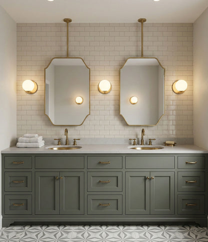Double suspended brass mirrors above green bathroom vanity with brass sinks.