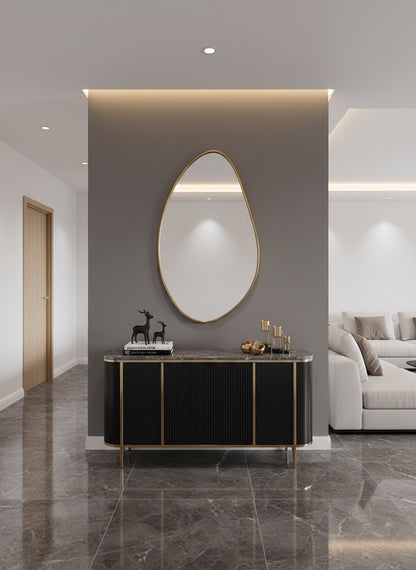 Brass mirror above black console in modern entryway