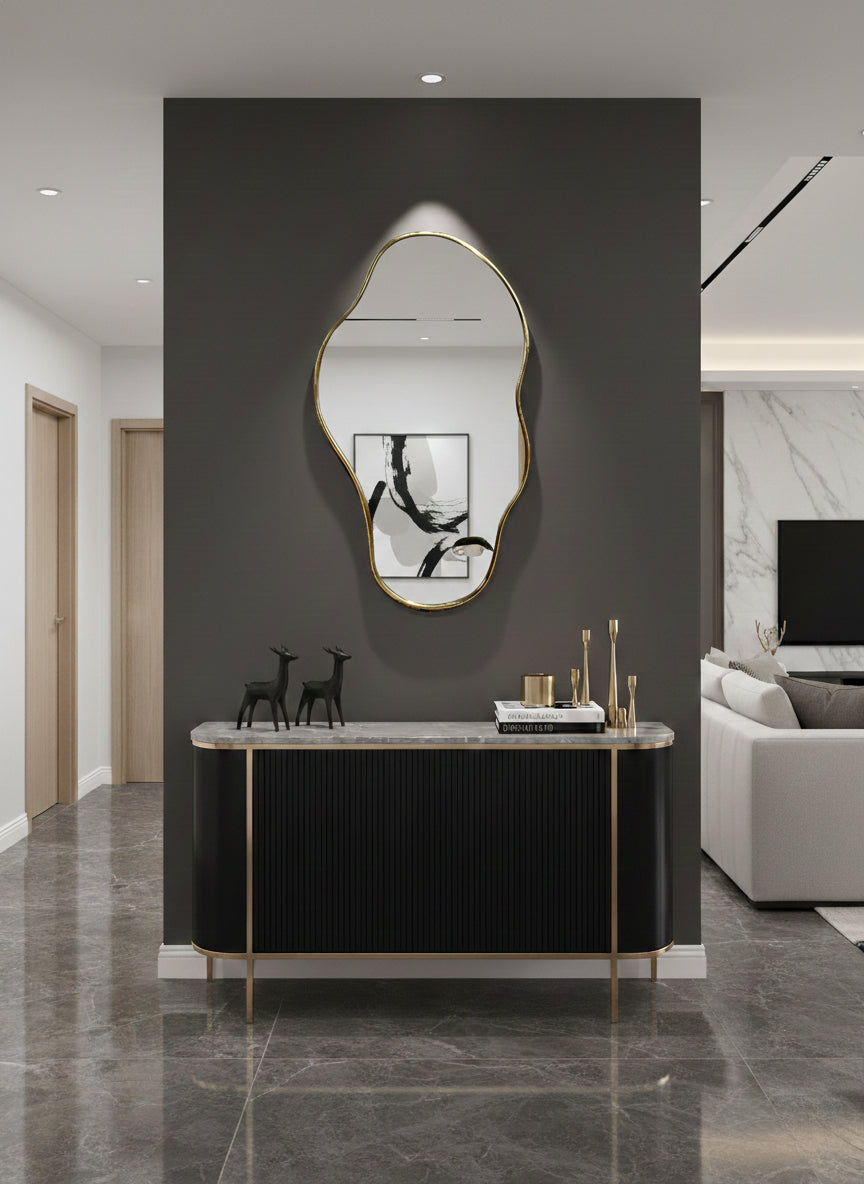 Asymmetrical brass mirror above black console
