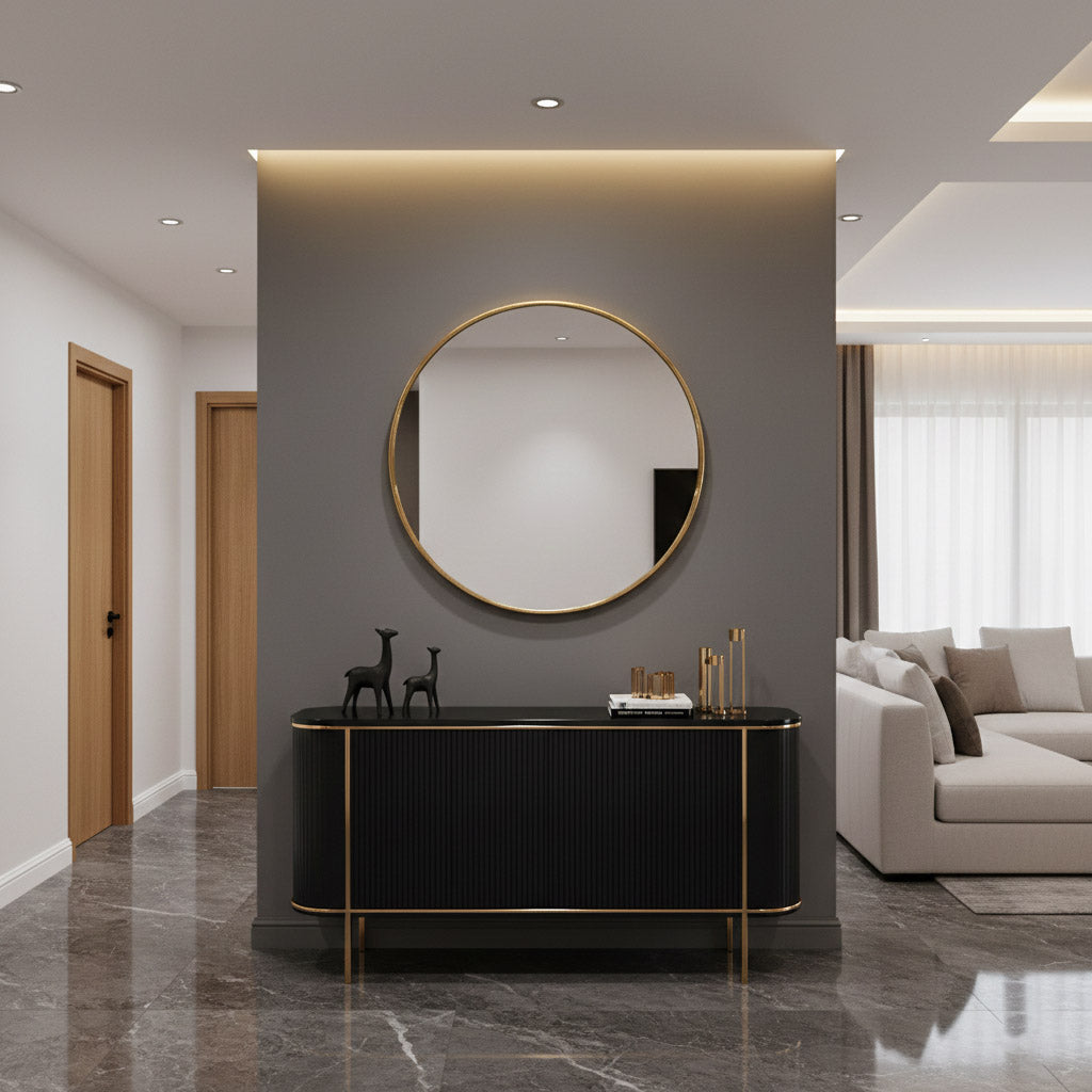 Round brass mirror above black console in modern entryway