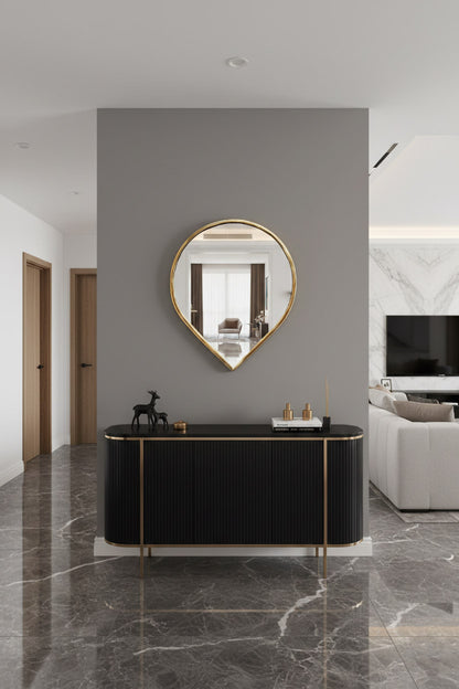 Teardrop brass wall mirror above black console table