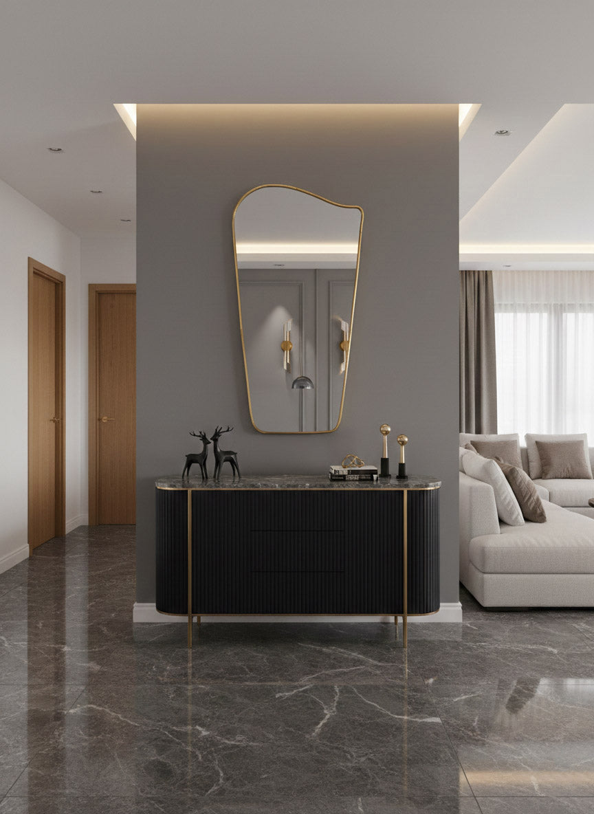 Wave brass mirror above black console in modern entryway interior