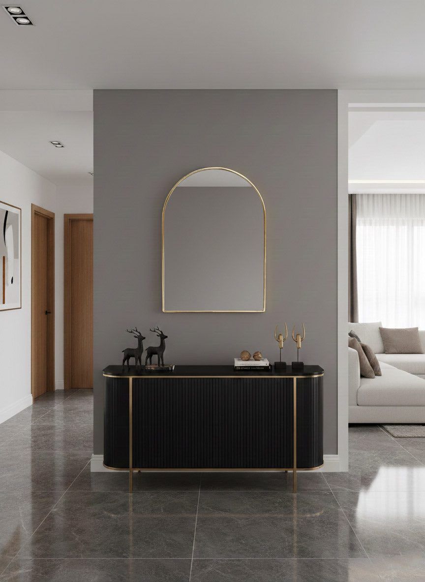 Modern arched brass mirror above black console table