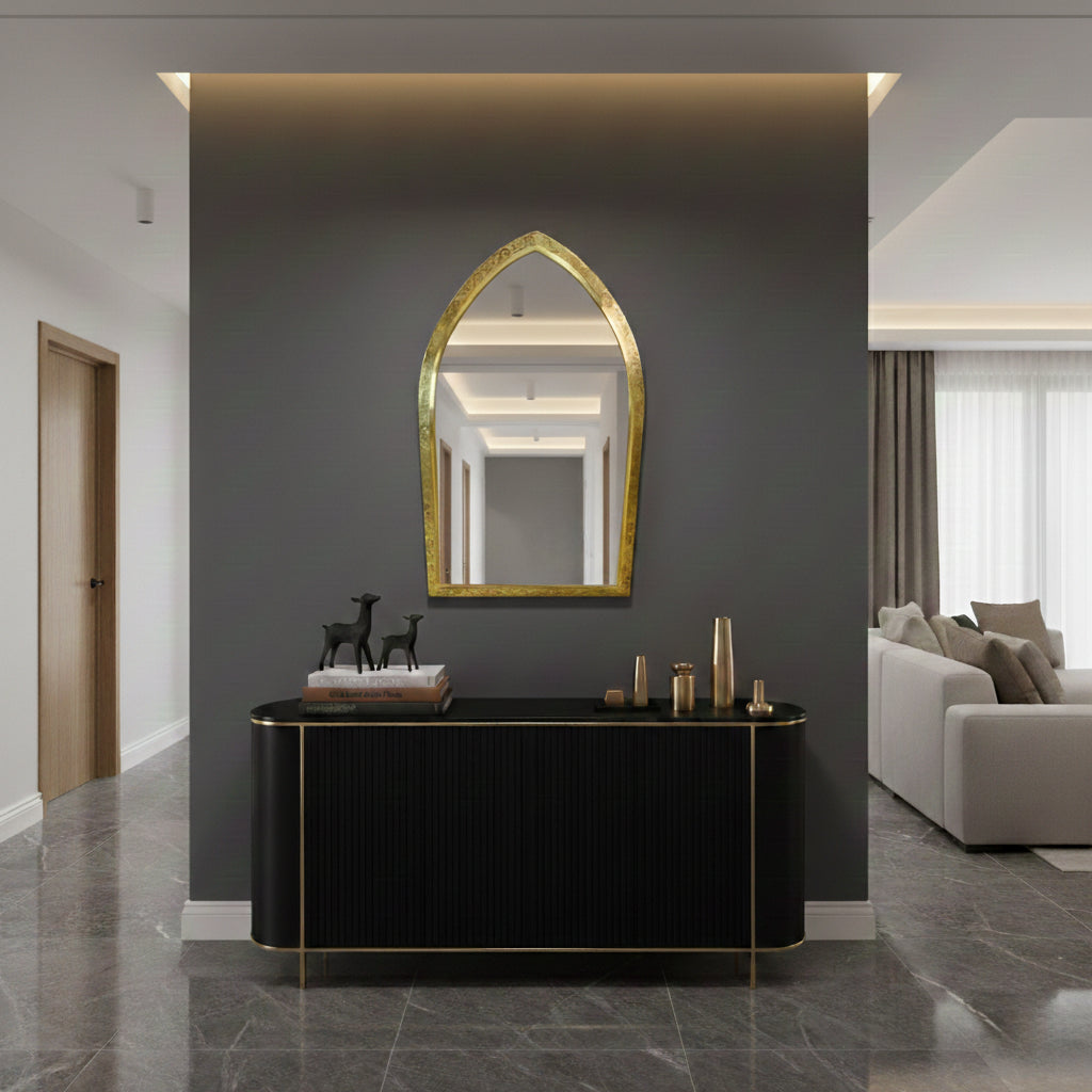 Arched brass mirror above black console in modern entryway