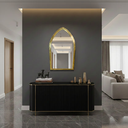 Arched brass mirror above black console in modern entryway