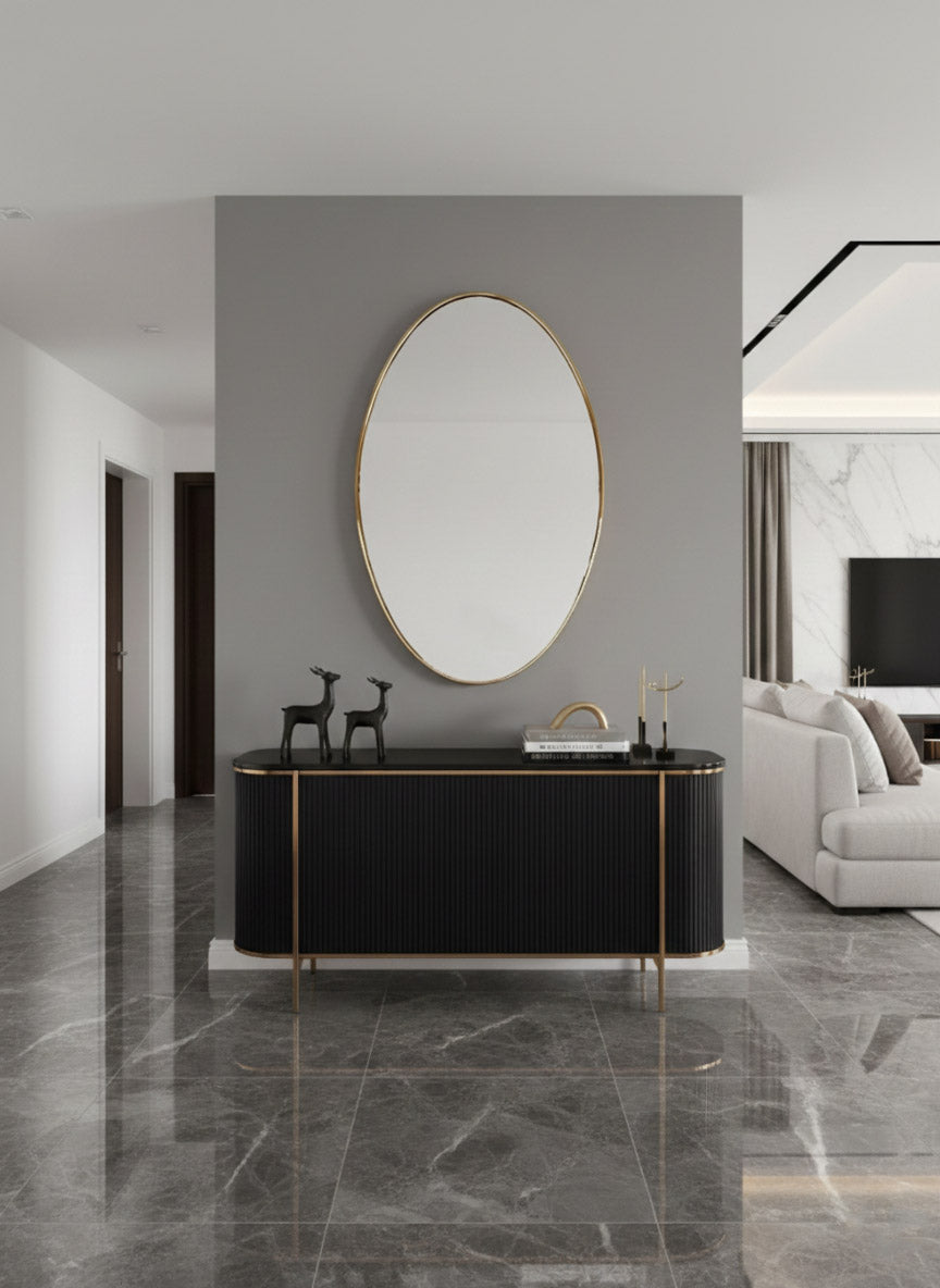 Gold oval wall mirror above a black console table in a modern hallway interior.