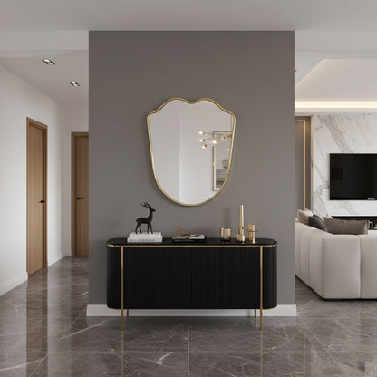Wavy-edge brass mirror above black console table